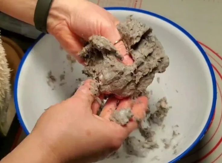 two hands are scooping out mud from a bowl