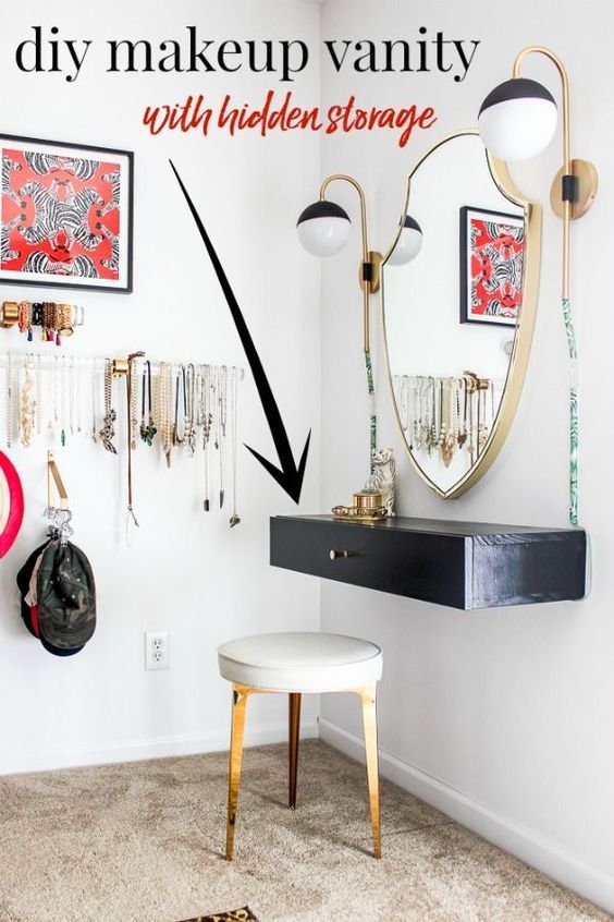 a white room with black and gold accessories on the wall, an oval mirror above a vanity table