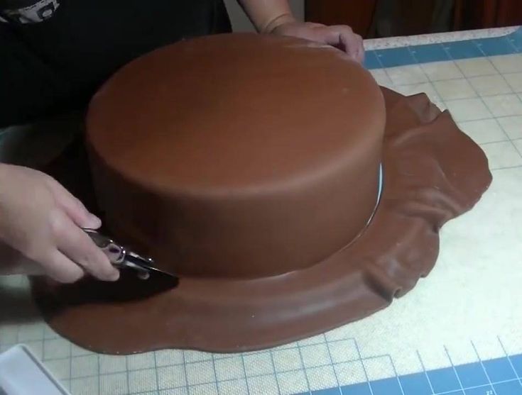 a person cutting into a chocolate cake with a pair of scissors