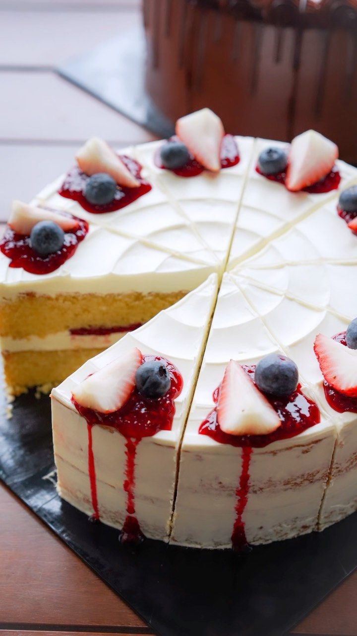 a white cake with berries and cream on top