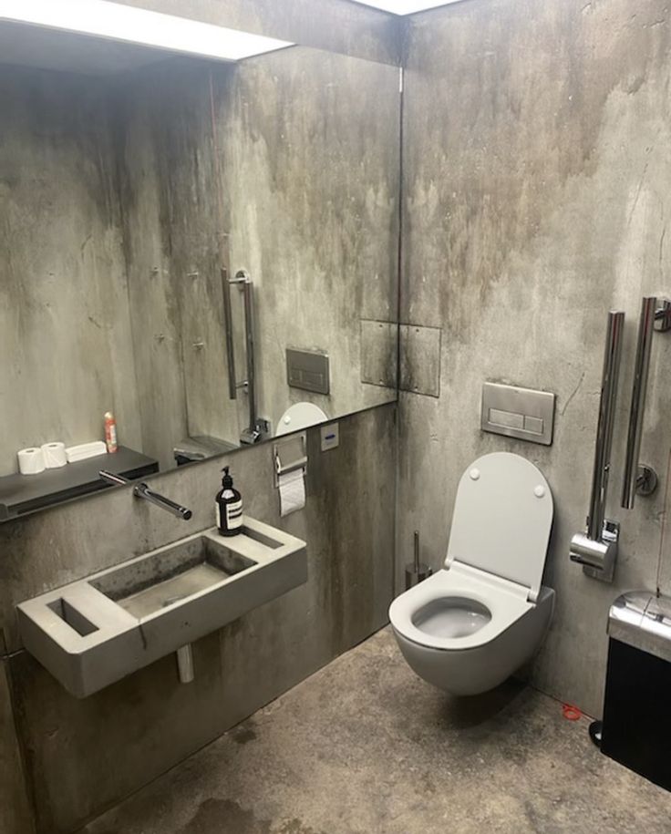 a bathroom with a toilet, sink and mirror on the wall next to each other