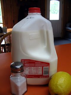 a jug of milk and two lemons on an orange table