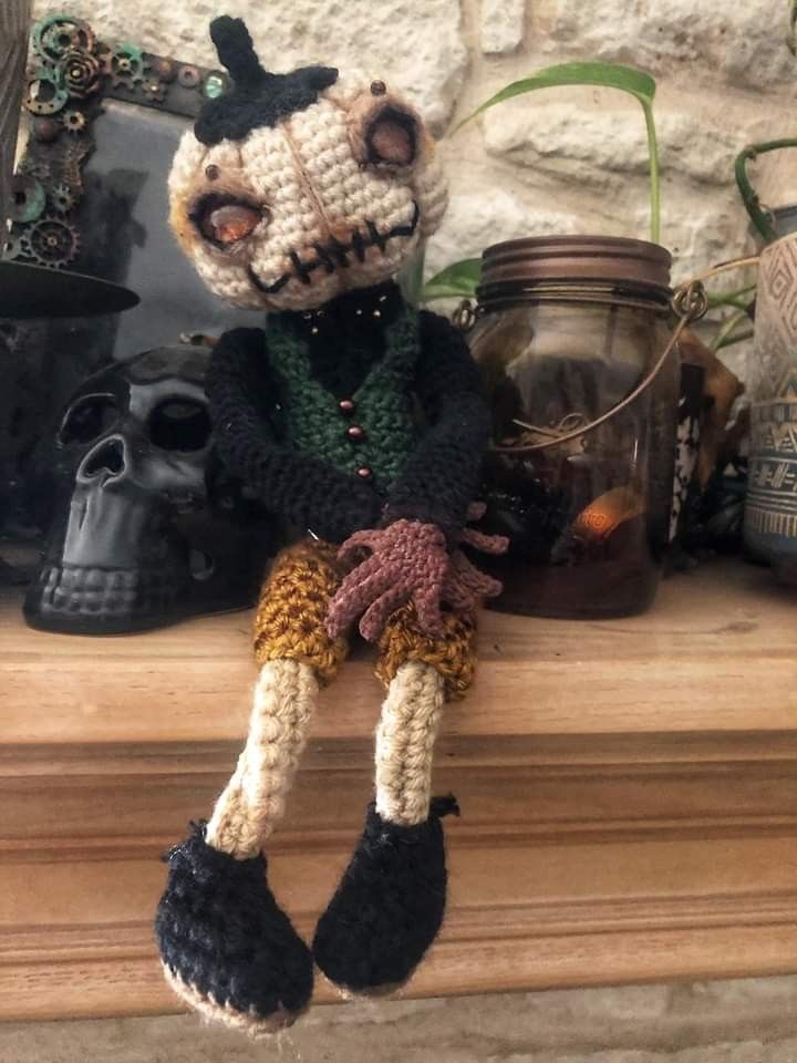 a crocheted doll sitting on top of a mantle