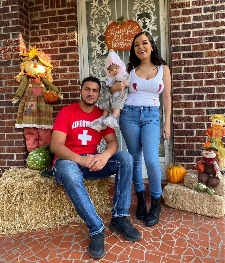 a man and woman are sitting on the porch with their baby in front of them