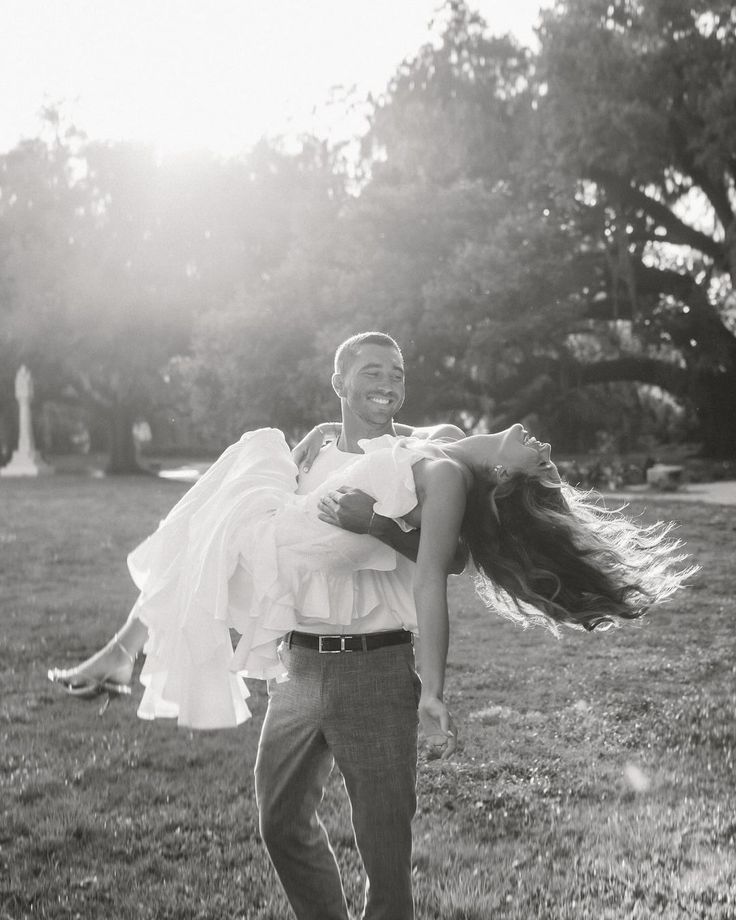 a man carrying a woman on his back in a field with trees and grass behind him