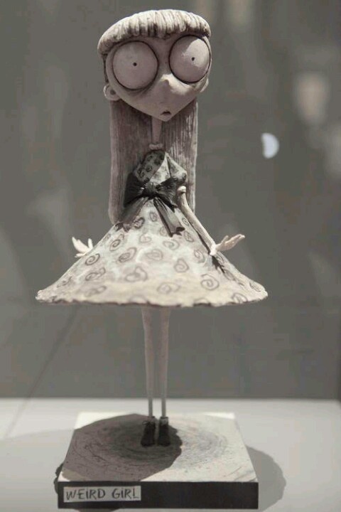 a sculpture of a girl with glasses and a dress on display in a glass case