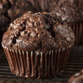 chocolate muffins cooling on a rack with other muffins in the background