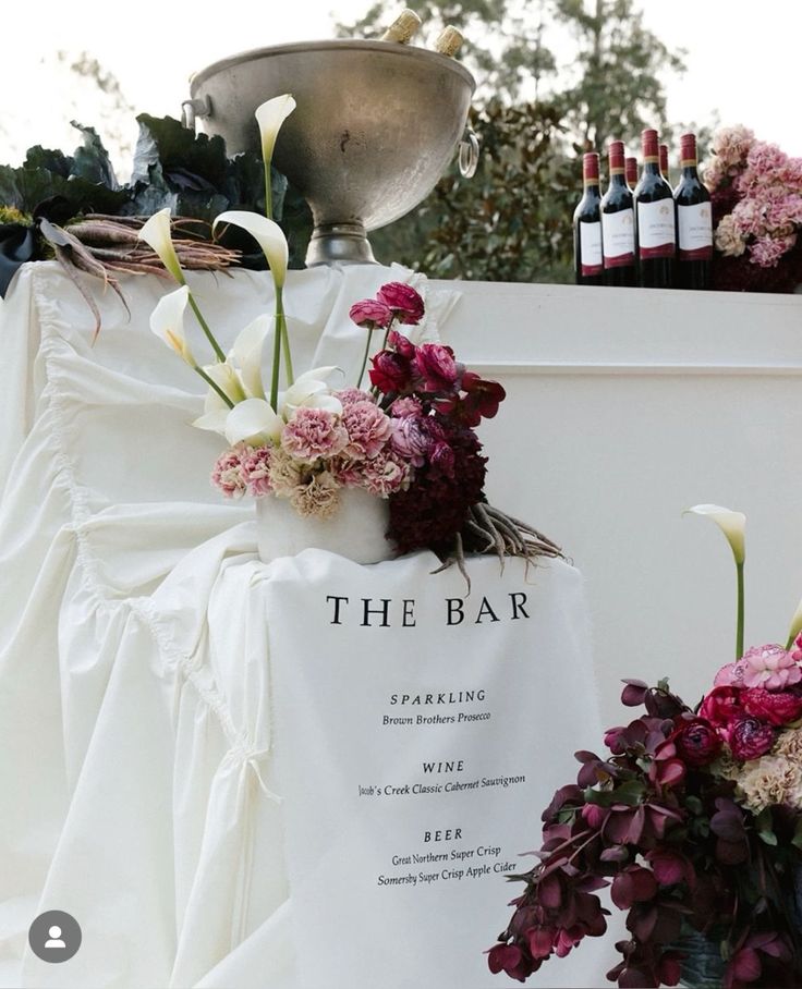 the bar sign is adorned with flowers and wine bottles in front of an outdoor display