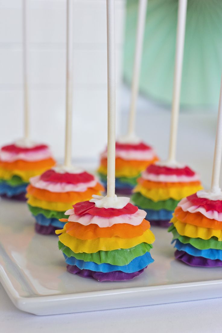 rainbow cake pops on a tray with white candles