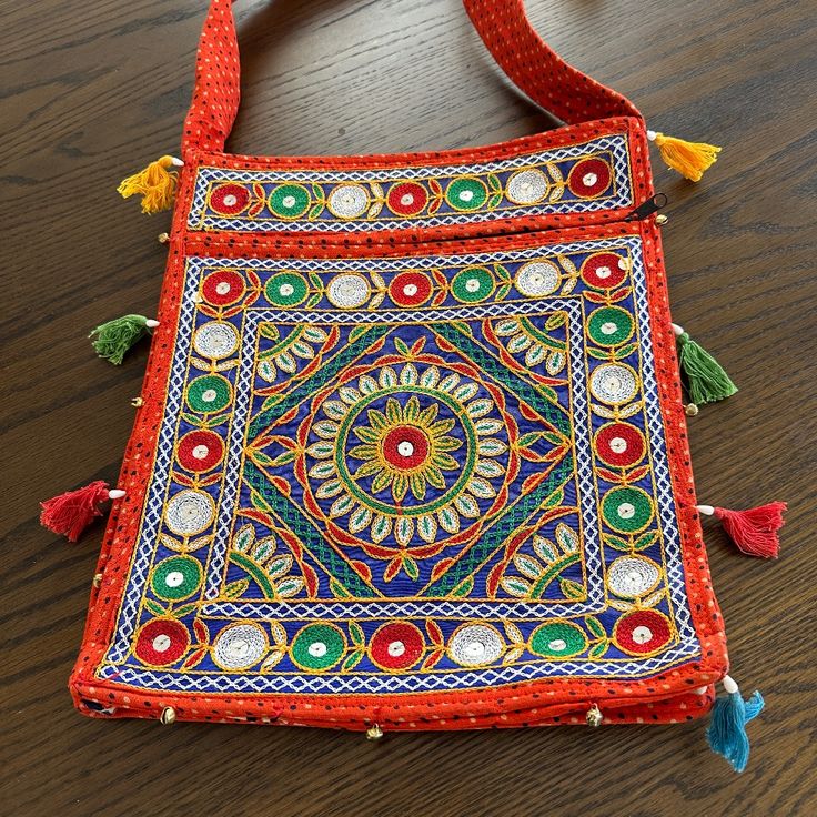 an embroidered bag with tassels and beads on the inside sits on a wooden surface