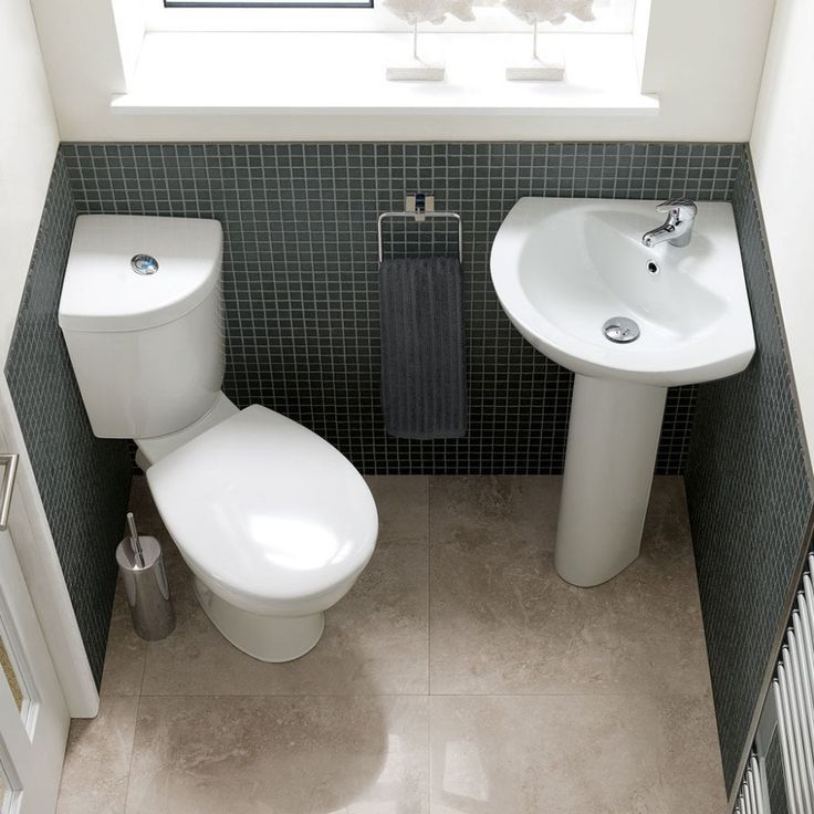 two toilets and a sink in a bathroom with tiled walls, flooring and white fixtures