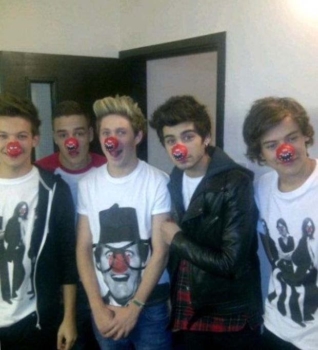 the boys are wearing clown noses and t - shirts with red nose rings on their mouths