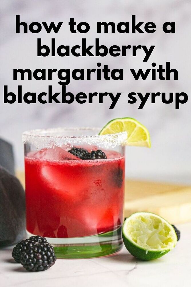 a blackberry margarita with blackberries and limes on the side