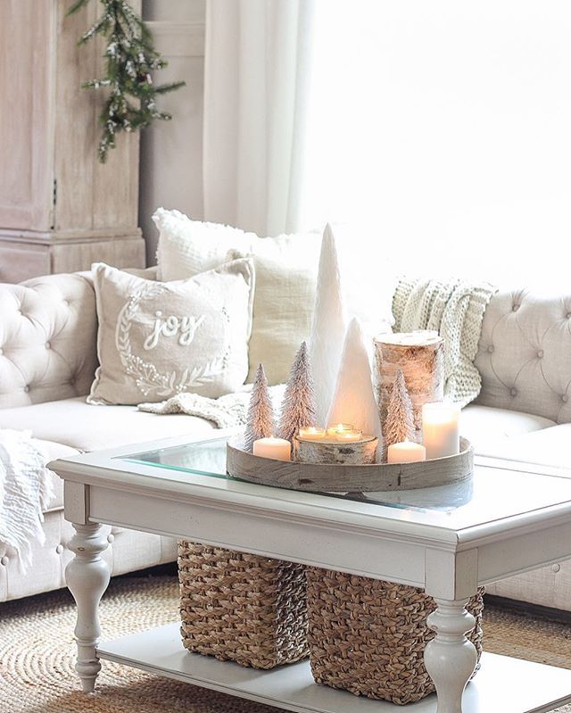 a white coffee table with candles on it in front of a couch and christmas tree