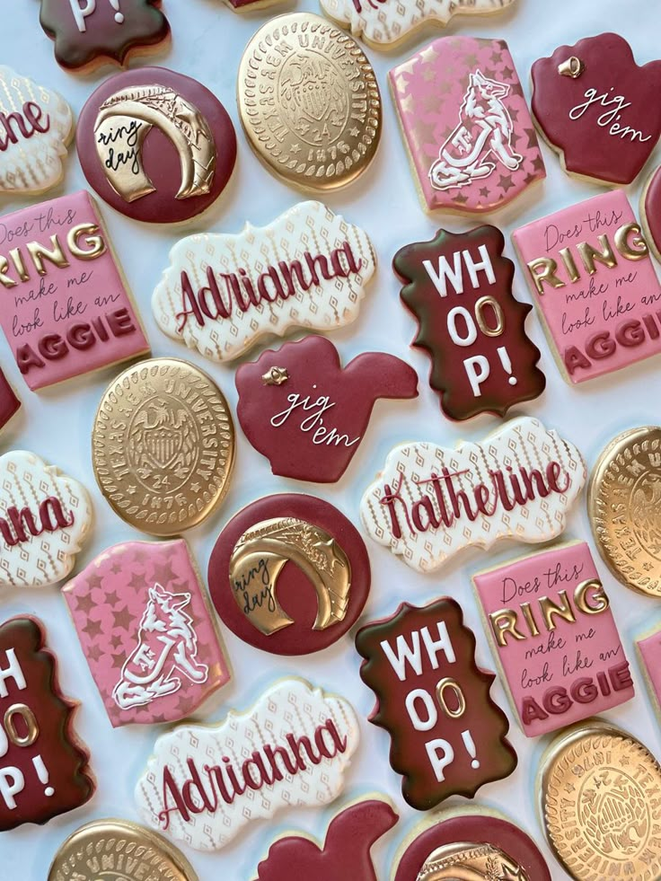 many different types of cookies are arranged on a white tablecloth with pink and gold accents