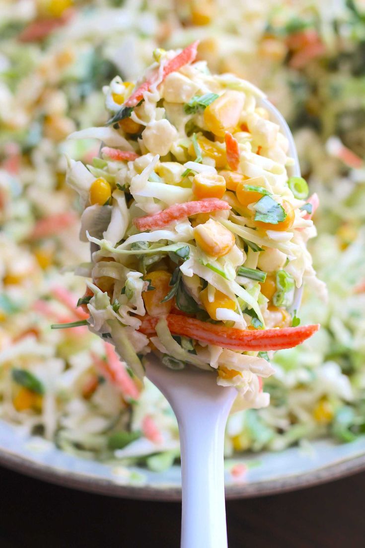 a spoon full of coleslaw salad on top of a wooden table