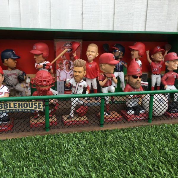 a group of baseball figurines sitting on top of a green fence in front of a dugout