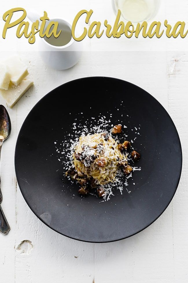 a black plate topped with food next to a cup and spoon on top of a white table