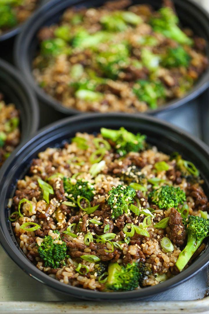 three black bowls filled with food on top of a metal tray and broccoli