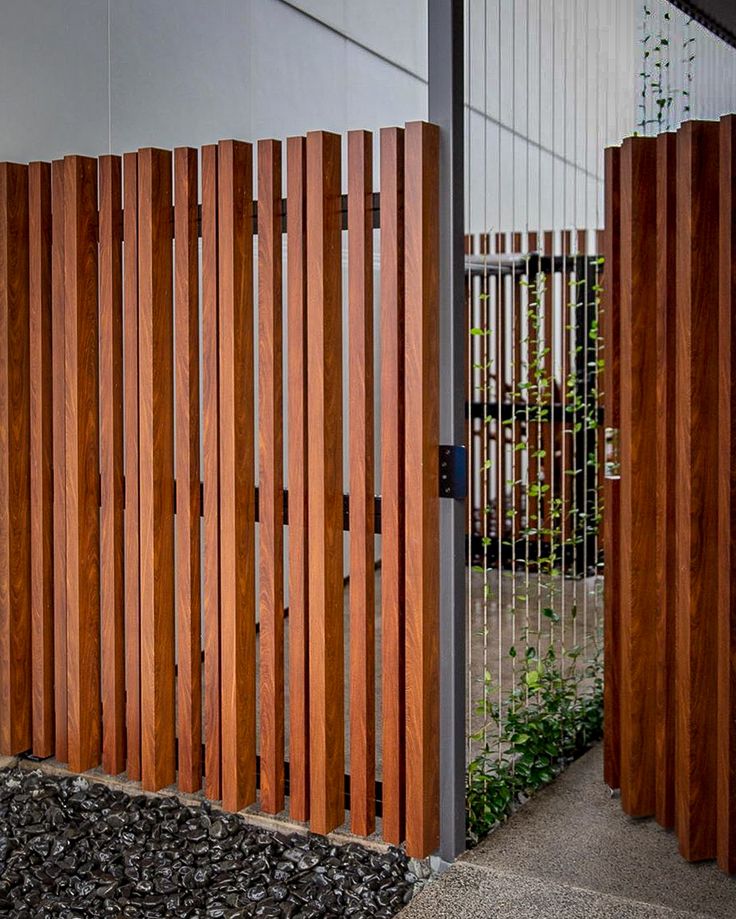 a wooden fence is next to a building with a metal gate on the outside and wood slats on the inside