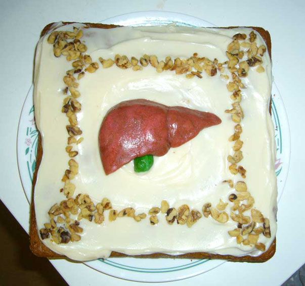 there is a cake that looks like a human liver on the plate with nuts around it