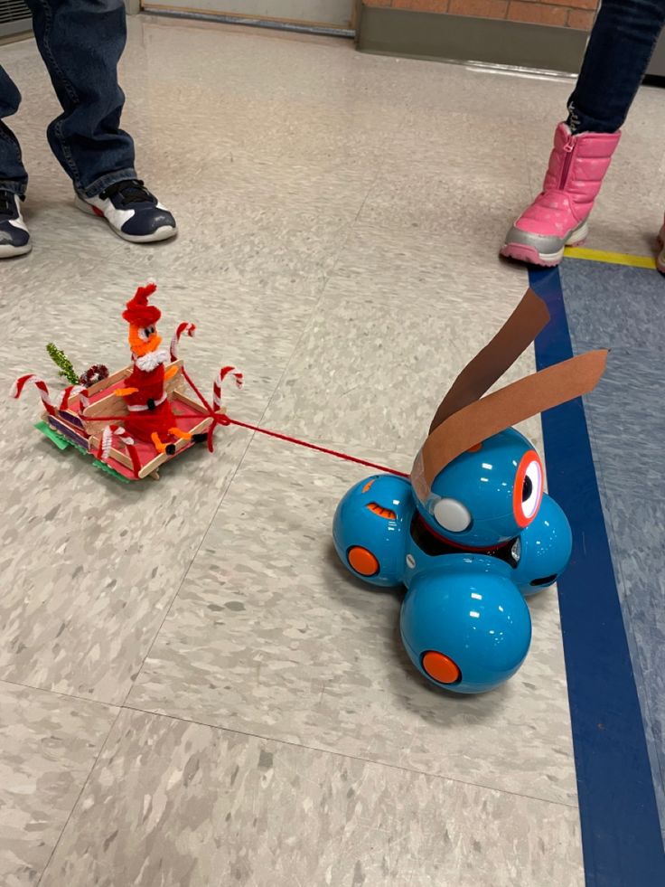 a blue toy car pulling a cardboard cut out of it's face on a string