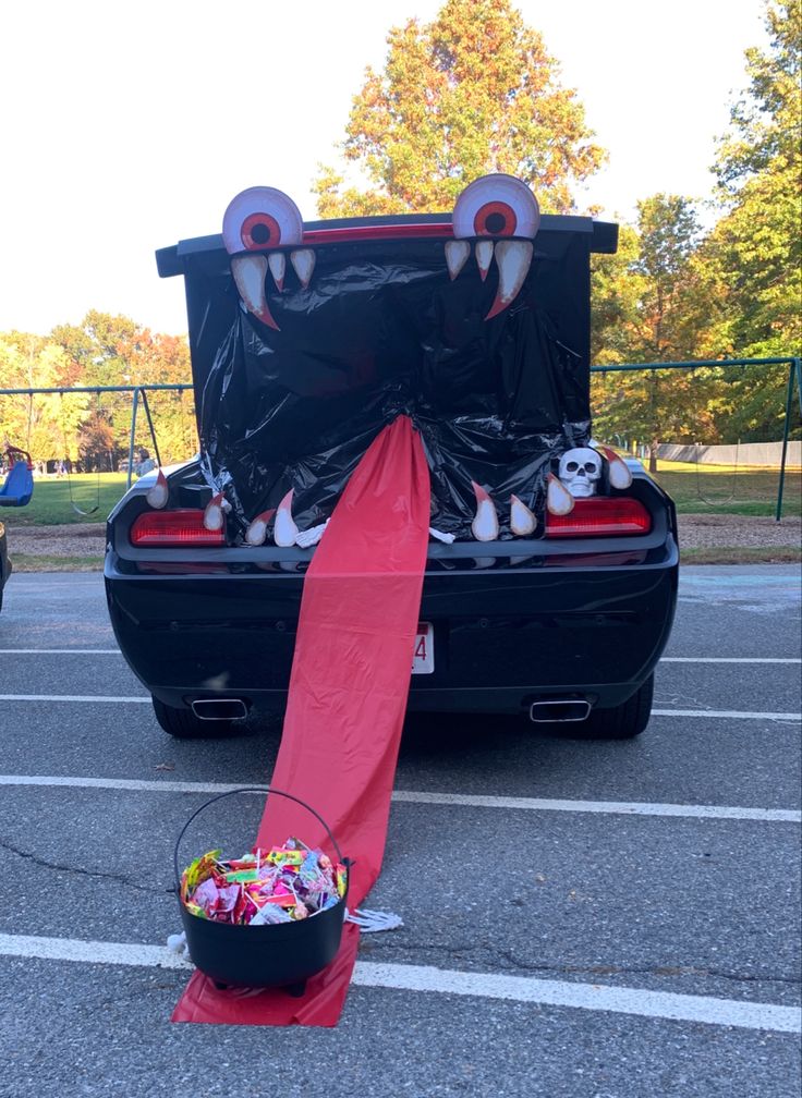 an open trunk with stuffed animals in it and a bucket full of candy on the ground