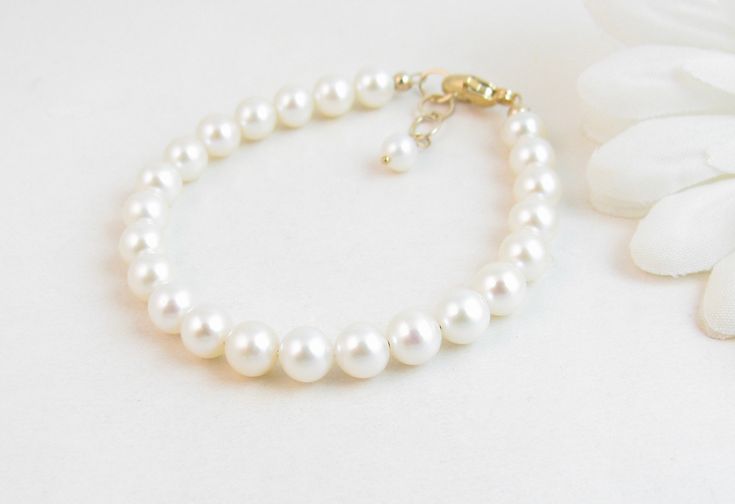 "A classic real freshwater pearl bracelet for newborn, infant, baby, child, little girl, tween or teen. This keepsake bracelet is created with Grade-A 5.5mm round freshwater pearls and a 14K gold-filled oval lobster clasp with a 1/2\" \"Grow with Me\" extender chain. Arrives packaged in my signature high-quality reusable canvas gift bag. Beautiful and ready for gift giving. S I Z I N G . G U I D E The bracelet should be 3/4\" larger than her snug wrist measurement. If you are unable to measure, Classic White Bracelets For Mother's Day, Elegant Pearl Jewelry For Baptism, Classic White Pearl Bracelet For Mother's Day, Elegant Adjustable Pearl Bracelet For Baptism, Elegant Pearl White Jewelry For Baptism, Classic Adjustable Jewelry For First Communion, Elegant Pearl Bracelet For First Communion, Elegant Pearl White Jewelry For First Communion, Elegant White Bracelets