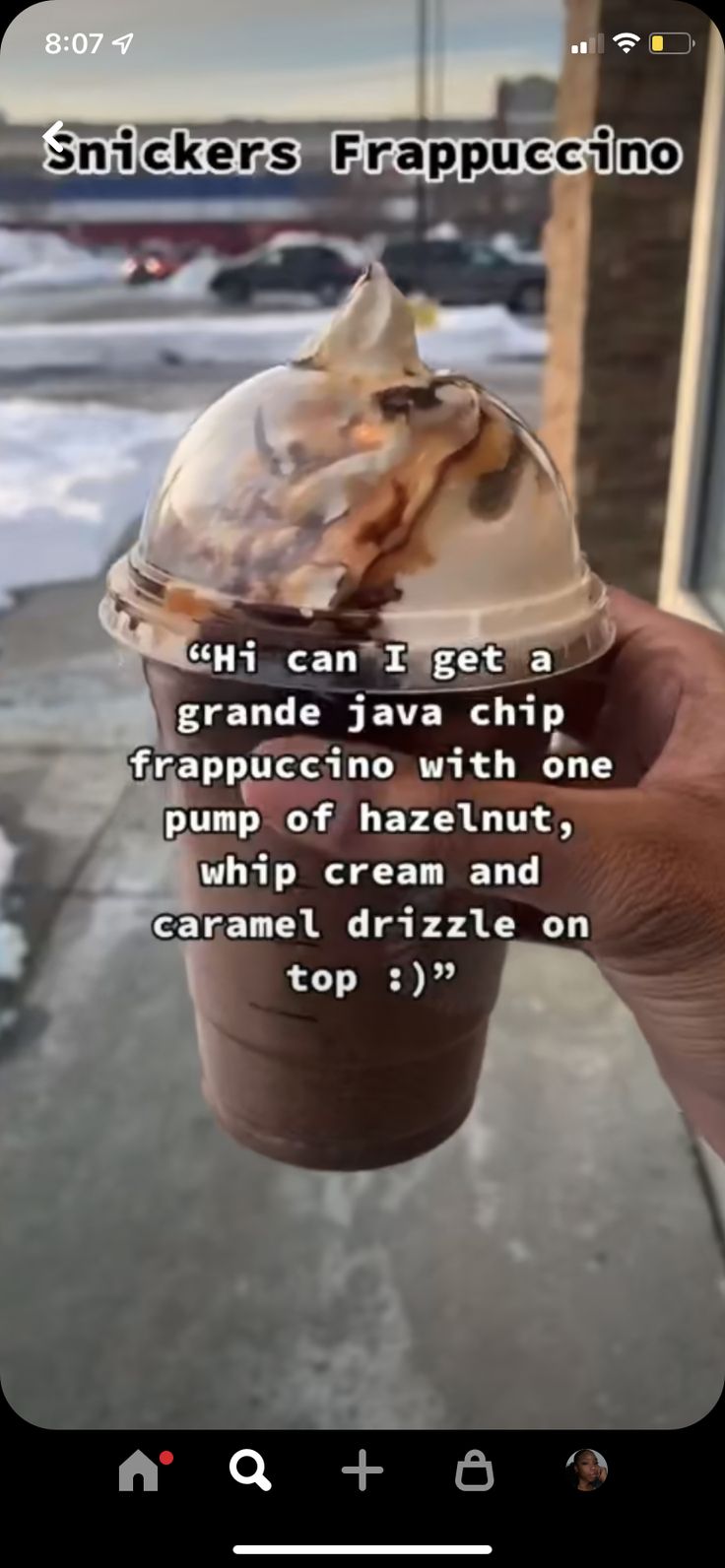 someone is holding up an ice cream sundae in front of a building with snow on the ground