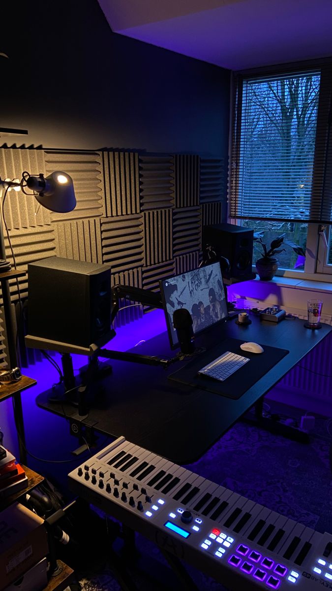 a room with several electronic devices and sound equipment on the desk in front of a window