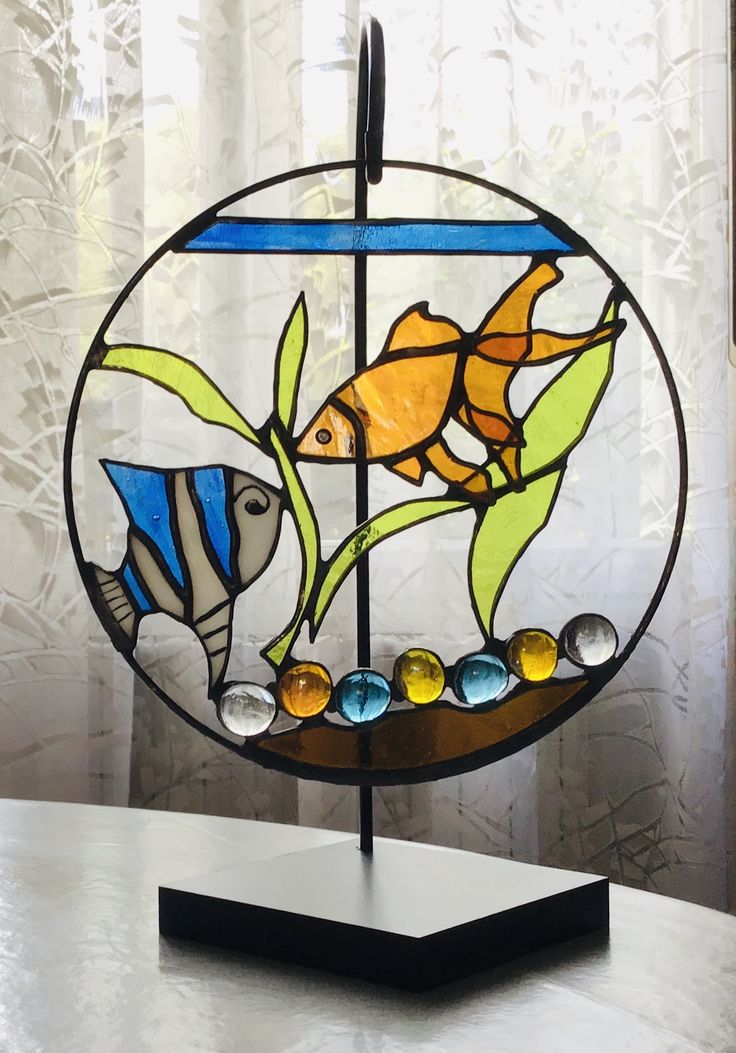 a stained glass window with two fish and bubbles in the water on top of a table