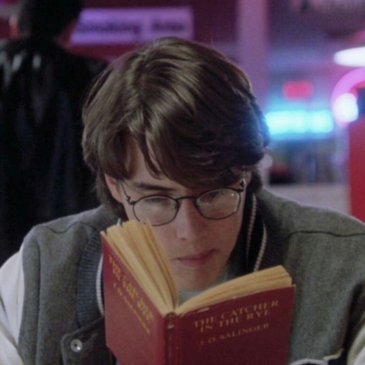 a young man wearing glasses reading a book