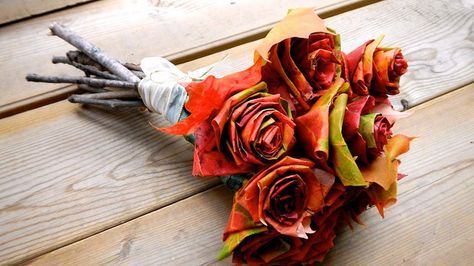 a bouquet of flowers sitting on top of a wooden table next to some sticks and leaves