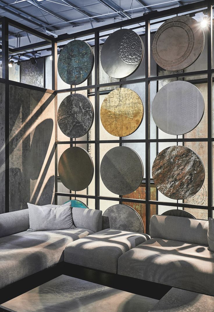 a living room filled with lots of gray couches and round mirrors on the wall