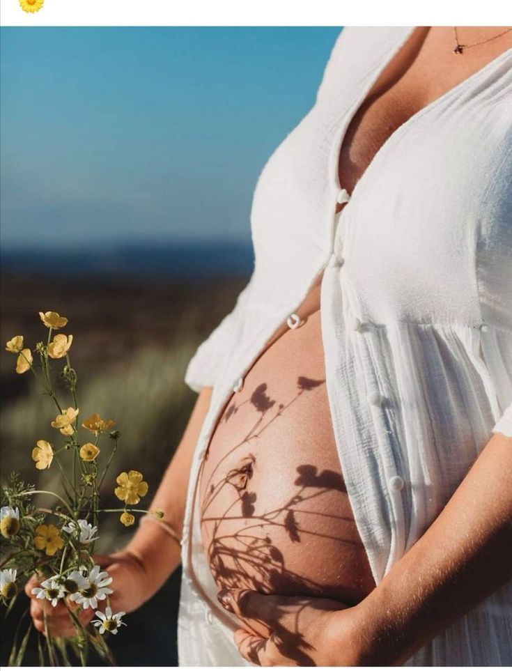 a pregnant woman holding flowers in her belly