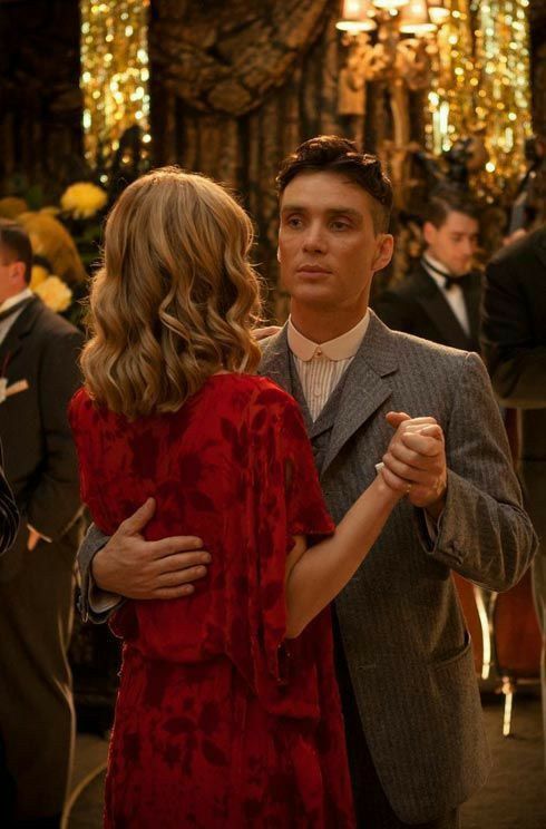 a man in a suit and tie standing next to a woman wearing a red dress