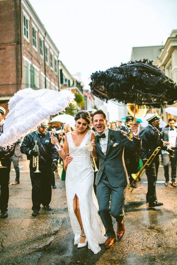 a newly married couple walking down the street with an umbrella in their hand and confetti being thrown around them