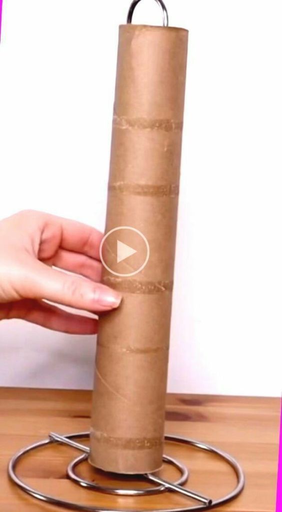 a person is holding a roll of toilet paper on a metal stand with a video playing below it