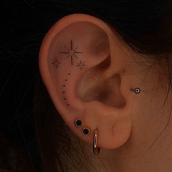 a woman's ear with three piercings on it