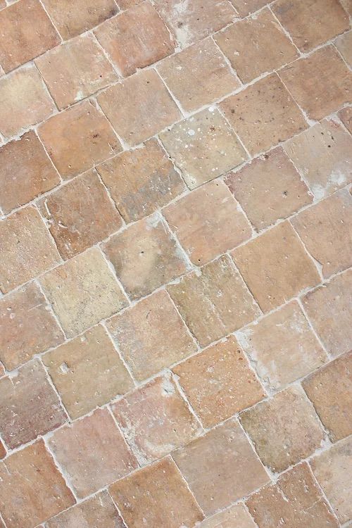 an orange and white cat laying on top of a brick floor