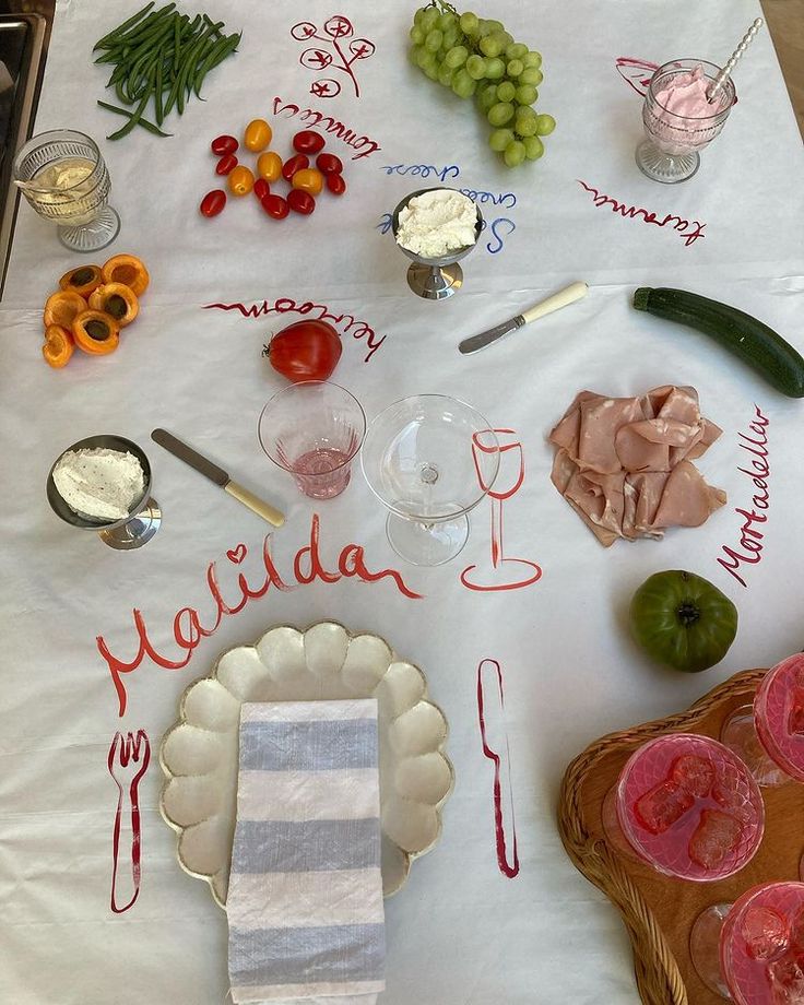 a table topped with lots of different types of food and drinks on top of a white table cloth