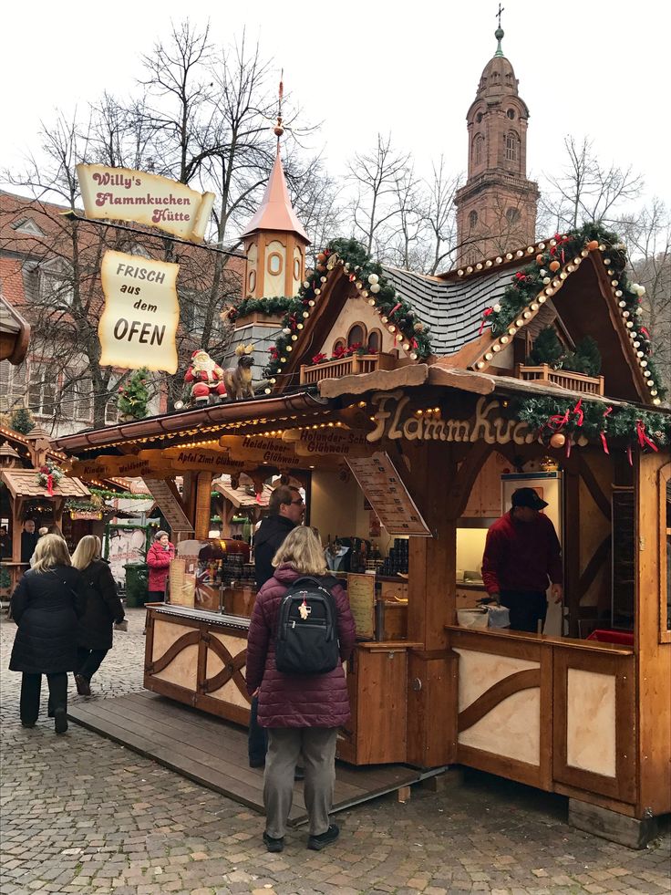 people are standing at an outdoor food stand with christmas decorations on the roof and around it