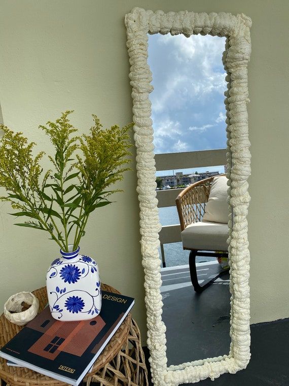 a mirror sitting on top of a table next to a vase