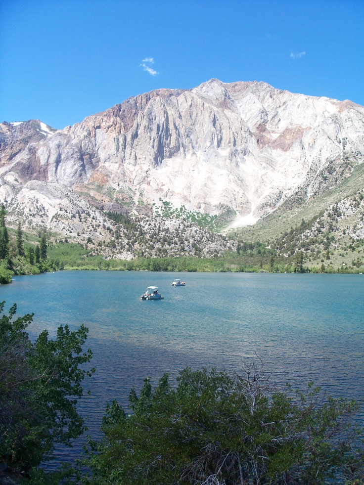 two boats floating on top of a lake surrounded by mountains