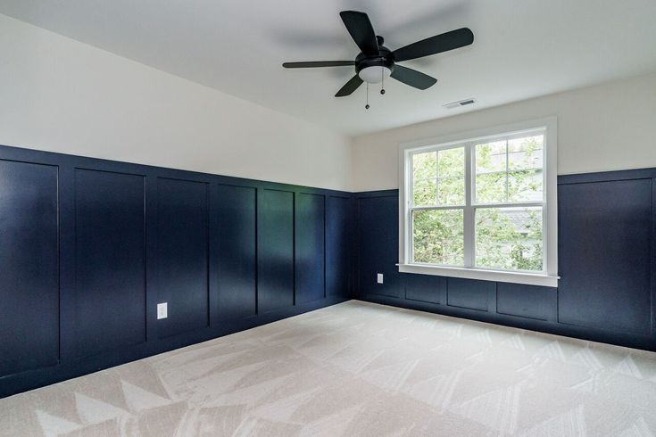 an empty room with blue painted cabinets and a ceiling fan