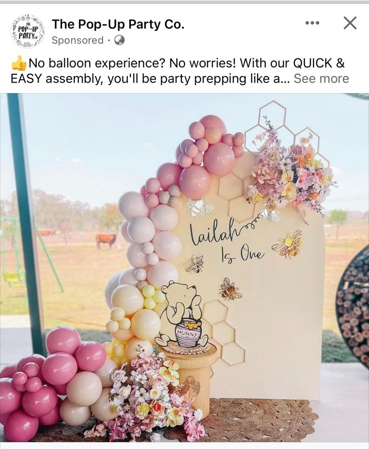 a cake with balloons and flowers on it is displayed in front of a party sign