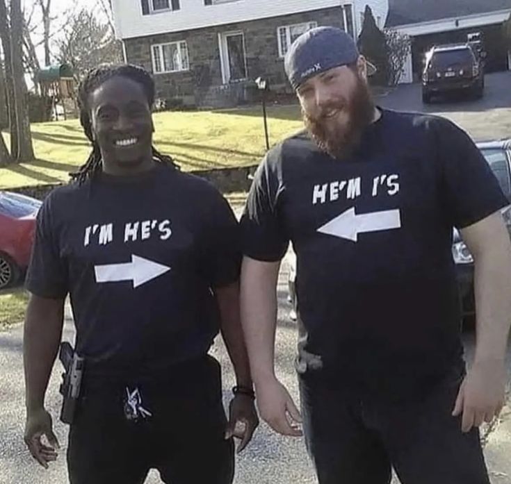 two men standing next to each other in front of a house wearing t - shirts with an arrow on it