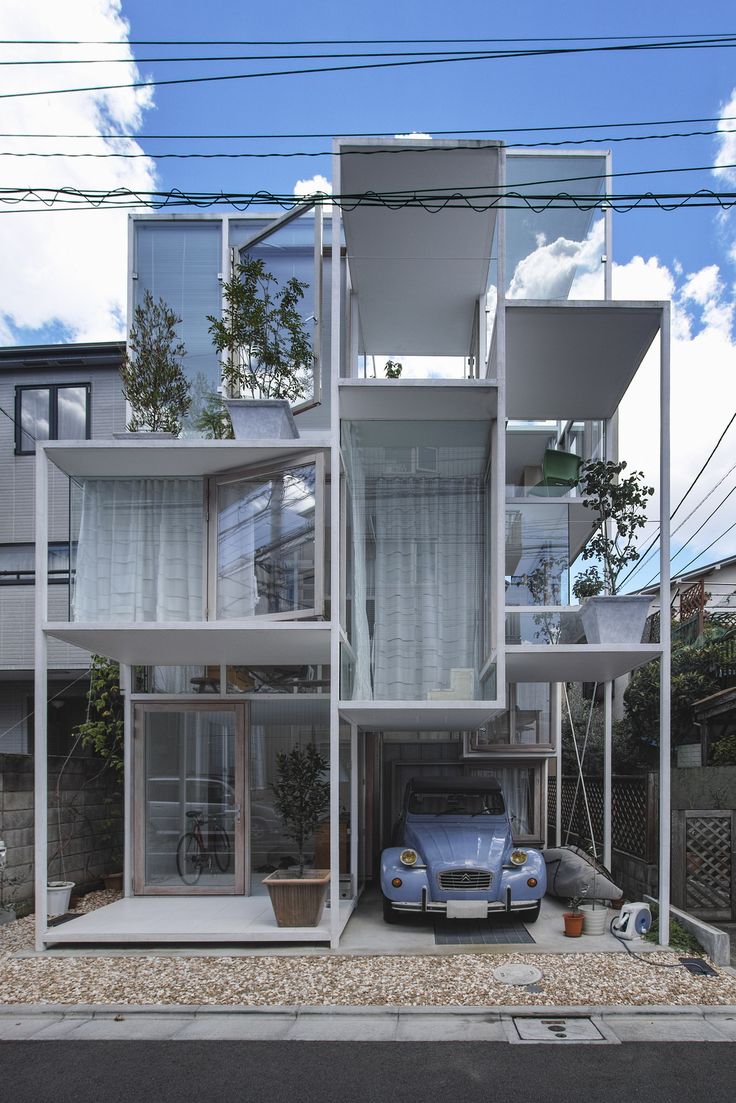 a car is parked in front of a house with multiple levels and balconies