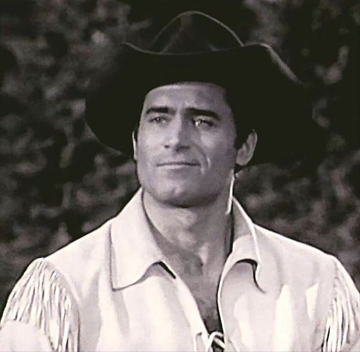 a black and white photo of a man wearing a cowboy hat