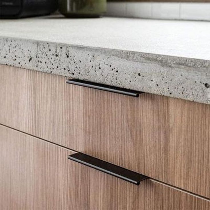 a kitchen counter with two black handles on it's side and a microwave in the background